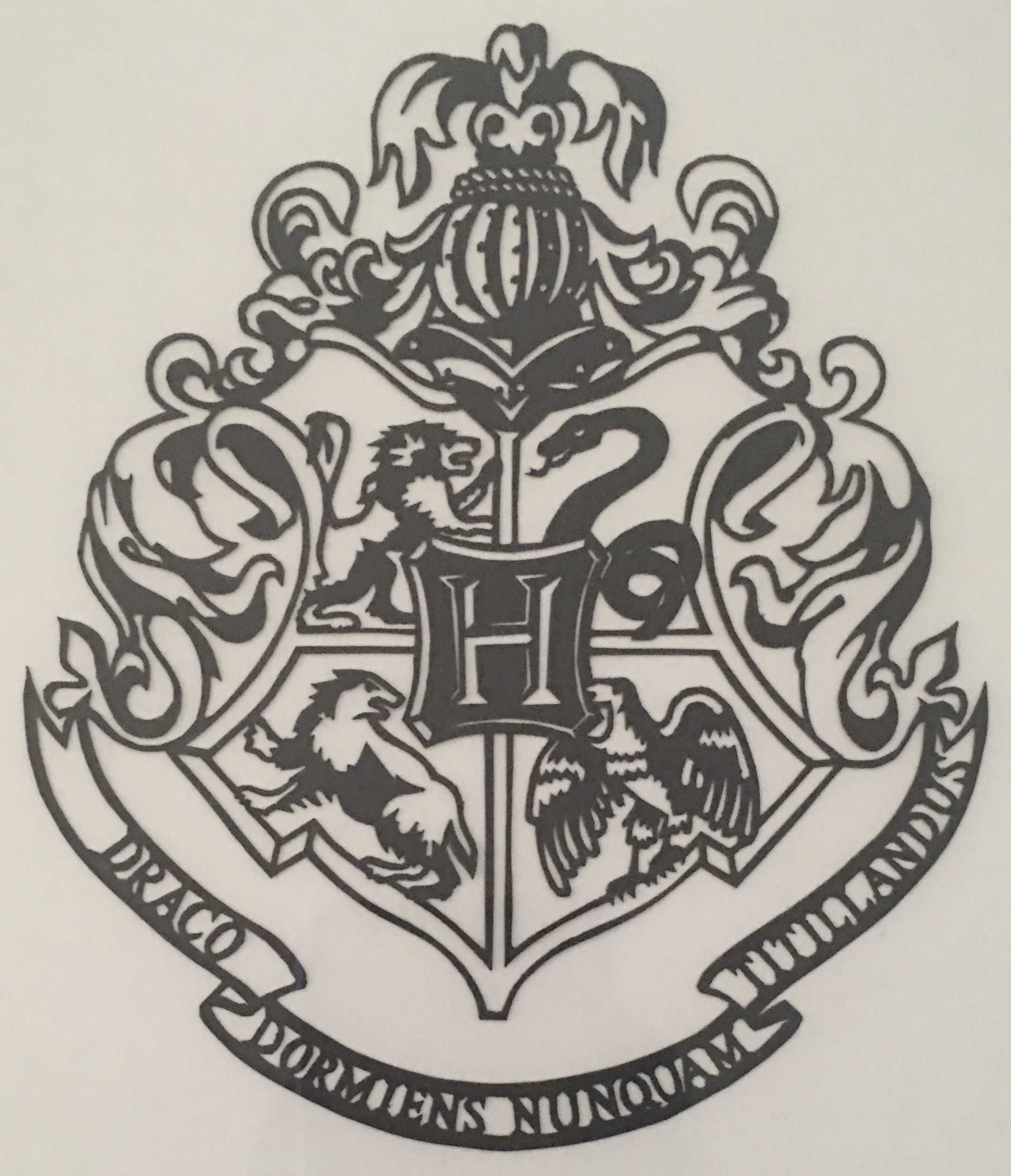 A black and white paper cutting of the Hogwarts Crest